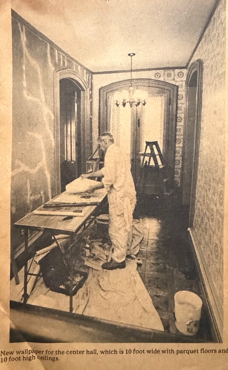 John Warga hanging wallpaper in a center hall, c. 1974